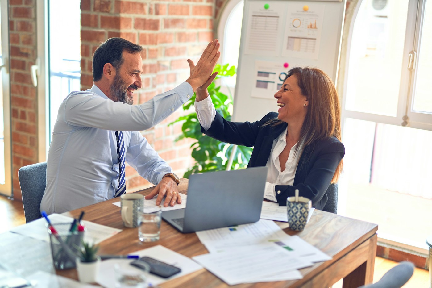Two business professionals smiling and celebrating progress during a meeting